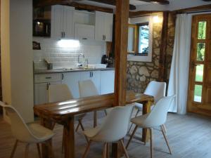 cocina con mesa de madera y sillas blancas en Takács vendégház, en Orfű