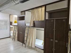 a room with bunk beds with ladder and cabinets at Hostel M-A Rooms Mate in Madrid