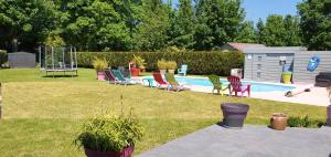 a backyard with a pool with chairs and a playground at Suite Parentale du Relais de Drugy in Saint-Riquier