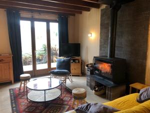 sala de estar con chimenea, mesa y sillas en maison forêt d'Aubrac , au coeur de la nature, en Prades-dʼAubrac