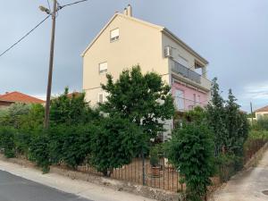 una casa rosa y blanca con árboles delante en New 4* apartment "Orto" in the center of Trogir, en Trogir