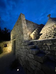 un edificio de piedra con una pared de piedra por la noche en Pietrefitte en Ostuni