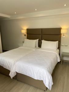 ein Schlafzimmer mit einem großen Bett mit weißer Bettwäsche und Kissen in der Unterkunft Golden View Residence in Dhërmi