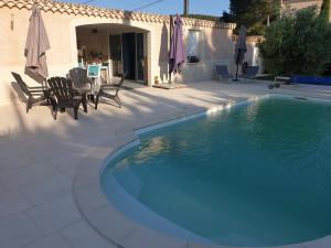 a swimming pool with chairs and a table next to a house at Moments de détente. in Carsan