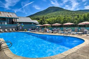 a large swimming pool with chairs and umbrellas at Village of Loon Mtn Condo with Fireplace and Balcony! in Lincoln