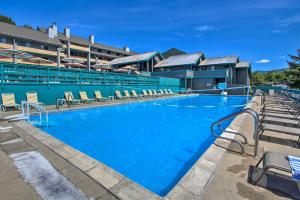 a large blue swimming pool with chairs in front of a building at Village of Loon Mtn Condo with Fireplace and Balcony! in Lincoln
