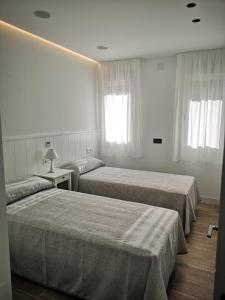 a hotel room with two beds and two windows at Casa Raquel,caminito del Rey in Valle de Abdalagís
