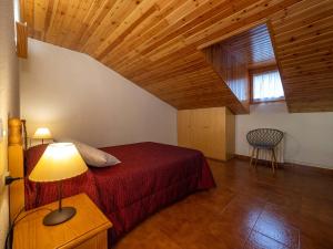 una camera con letto rosso e soffitto in legno di Casa rural Quintana - Montanuy a Montanúy