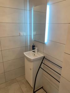 a white bathroom with a sink and a mirror at Domek Pensjonat Syrena in Krynica Morska