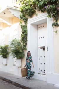 een vrouw in een jurk die voor een gebouw staat bij Hotel Casa Lola Deluxe Gallery in Cartagena