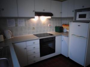 a kitchen with white cabinets and a stove and a refrigerator at Redwood Apartment in Killarney