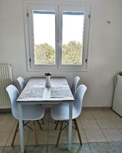 a dining room table with white chairs and a vase on it at Paros Iliahtides Apartments near Golden Beach in Márpissa