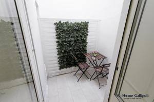 G-Home Gallipoli rooms and suite في غالّيبولي: شرفة صغيرة مع طاولة وجدار أخضر