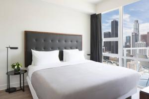 a bedroom with a large white bed and a large window at Luxury Highrise Living Downtown LA in Los Angeles