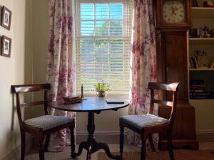 uma mesa e duas cadeiras em frente a uma janela com um relógio em HORTUS HOUSE - Regency style apartment with attached parking em Brixham