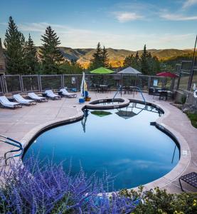 a swimming pool with chairs and tables and mountains in the background at Timberline Condominiums 3 Bedroom plus loft Deluxe Unit D3E in Snowmass Village