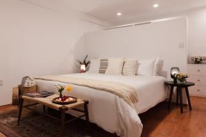 um quarto com uma grande cama branca e uma mesa em Jardín Roma By The Local Way em Cidade do México