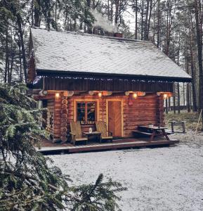 a log cabin in the woods with a table and chairs at Piparmētras in Mērsrags