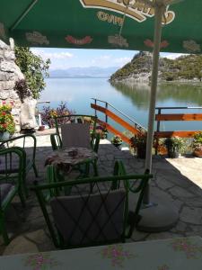 a table and chairs under an umbrella with a view of a lake at Holiday home Raduš in Virpazar +58 photos