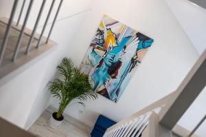 a painting hanging on a wall next to a plant at Gerika guest house in Palanga