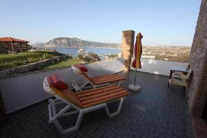 a patio with two chairs and an umbrella on a balcony at Panorama Studios in Kefalos