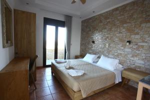 a bedroom with a bed and a stone wall at Panorama Studios in Kefalos