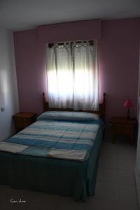 1 dormitorio con 1 cama y ventana con manta azul en Hostal Costa de la Luz, en Chipiona