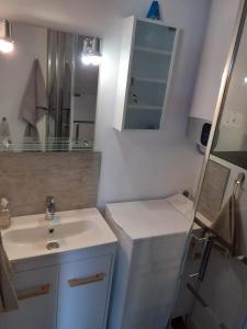 ein weißes Badezimmer mit einem Waschbecken und einem Spiegel in der Unterkunft Appartement T2 Ensoleillé au Barcarès in Le Barcarès