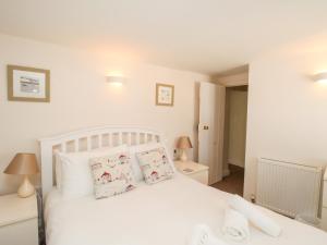 a bedroom with a white bed with pillows at Firkin Cottage in Weymouth