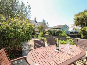 a wooden table with two chairs and a bottle of wine at Firkin Cottage in Weymouth