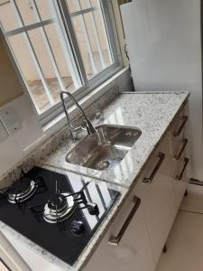 a kitchen counter with a sink and a stove at Apto JK Universitário - Express in Santa Cruz do Sul
