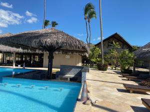 a resort with a swimming pool with a straw umbrella at Cumbuco Eco Paradise apto com varanda in Cumbuco