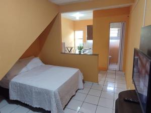 a small bedroom with a bed and a kitchen at Loftzinho Angra dos Reis in Angra dos Reis