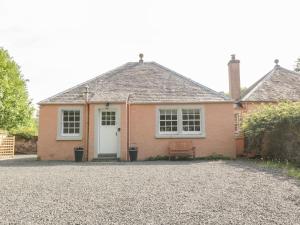 una casa de ladrillo con una puerta blanca y un banco en Maisie's Cottage, en Dunblane