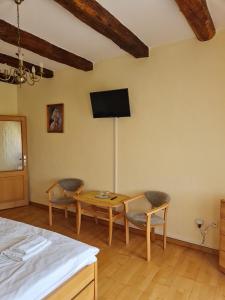 um quarto com uma mesa e cadeiras e uma televisão na parede em Andrišov dom penzion em Tvarožná