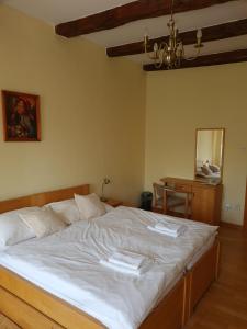 um quarto com uma cama com lençóis brancos e uma mesa em Andrišov dom penzion em Tvarožná