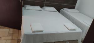 two beds in a room with white sheets and pillows at Pousada Barrancas in Piranhas