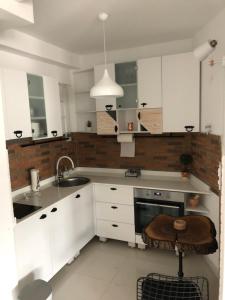 eine Küche mit weißen Schränken, einer Spüle und einem Stuhl in der Unterkunft Artistic Luxury in Skopje