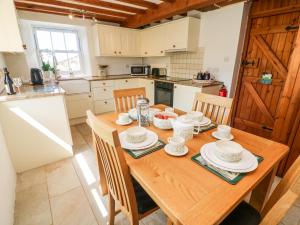 a kitchen with a wooden table and chairs and a kitchen with white appliances at Spout Cottage in Sedbergh