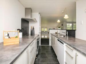 una cocina con armarios blancos y encimeras de acero inoxidable en 6 person holiday home in Bl vand, en Blåvand