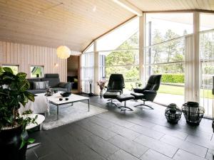 a living room with a couch and chairs and windows at 8 person holiday home in Bl vand in Blåvand