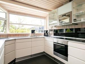 a kitchen with white cabinets and a large window at 8 person holiday home in Bl vand in Blåvand