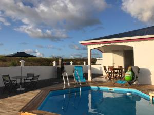a swimming pool with a patio and a house at YOLANDA HIBISCUS in Le Moule