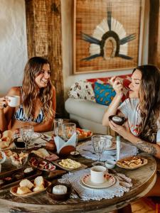 zwei Frauen sitzen an einem Tisch mit Essen in der Unterkunft Casa Amada in Arraial d'Ajuda