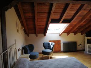 ein Schlafzimmer mit 2 Stühlen und einem Bett sowie Holzdecken in der Unterkunft Room in BB - Angelas Garden Inn in Santander