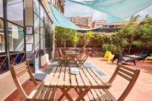 a patio with tables and chairs and a blue umbrella at ELLA Guest House Barcelona in Barcelona