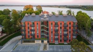an aerial view of a red building with a lake at Apartamenty BALTIVIA Olimpijska 2 in Mielno