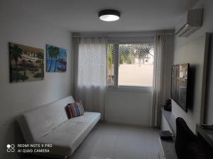 uma sala de estar com um sofá branco e uma janela em Lindo apartamento ao lado do Park Shopping Canoas em Canoas