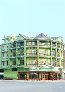 a large green building with windows at Angkor Comfort Hotel in Battambang