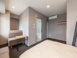 a small bedroom with a bed and a chair at Super Hotel Nagoya Shinkansenguchi in Nagoya